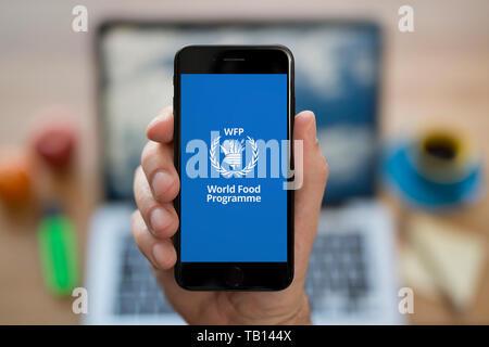 Ein Mann schaut auf seinem iPhone die zeigt das World Food Programm Logo (nur redaktionelle Nutzung). Stockfoto