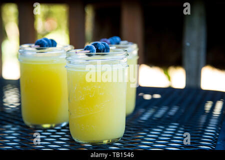 3 Mimosas in Mason Gläser mit blaubeere Spieß garnieren, auf Terrasse Tisch. Stockfoto