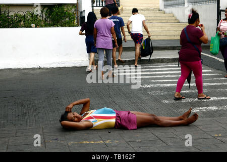 ANTIPOLO CITY, Philippinen - 21. MAI 2019: Eine obdachlose Frau liegt auf der Straße vor einer Kirche, wo Sie bittet um Almosen von Passanten. Stockfoto