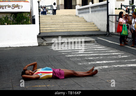 ANTIPOLO CITY, Philippinen - 21. MAI 2019: Eine obdachlose Frau liegt auf der Straße vor einer Kirche, wo Sie bittet um Almosen von Passanten. Stockfoto