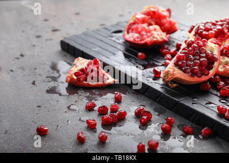 Holz- und Stücke reifer Granatapfel auf grauem Hintergrund Stockfoto