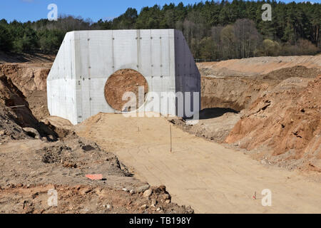 Große konkrete Collector für kanalrohre und Haufen von Sand mit Spuren von schwerer Ausrüstung Räder auf einer Baustelle im Wald. Stockfoto