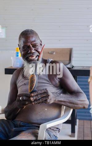 Tiwi Islander Künstler stolz Unterzeichnung eines seiner Tiwi vogel Holzschnitzereien Stockfoto