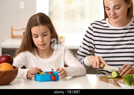 Mutter vorbereiten Schule Mittagessen für ihre Tochter zu Hause Stockfoto