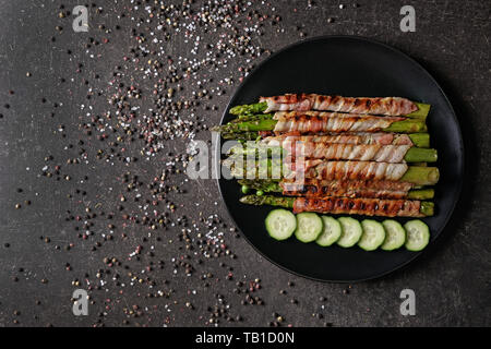 Platte mit Speck umwickelt Spargel auf Graue Tabelle Stockfoto