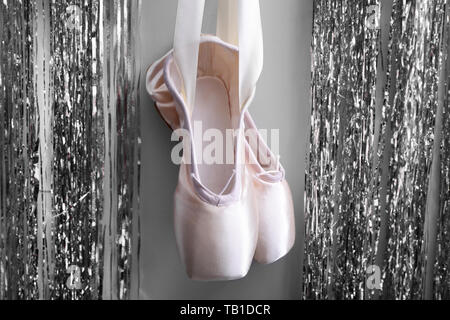 Hängende Ballett Schuhe mit silbernem Lametta auf graue Wand Stockfoto