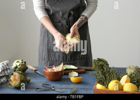 Frau bereitet leckere rohe Artischocken in der Küche Stockfoto