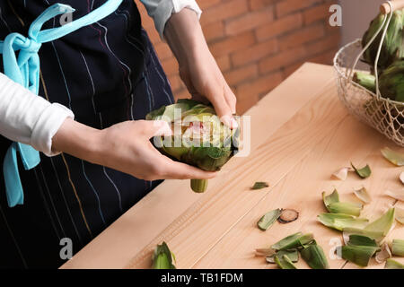 Frau bereitet leckere rohe Artischocken in der Küche Stockfoto