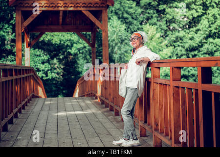 Aktive Dame stehend auf den braunen Holzbrücke Stockfoto