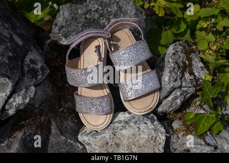 Ein paar neue Suche verlassene Mädchen sparkly Sandalen hinter sich gelassen auf einem Felsen, niemand im Bild Stockfoto