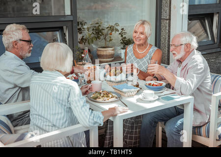 Positiv erfreut ältere Menschen das Abendessen auf der Terrasse Stockfoto