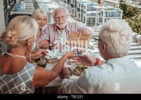 Freundliche ältere männliche Person, die Geschenkverpackung Stockfoto