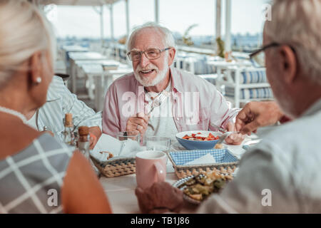 Fröhliche grauhaariger Mann hören auf seine Freunde Stockfoto