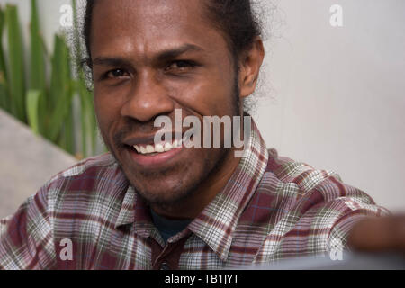 Junge schwarze Mann selfie und lächelnd in die Kamera, Papua junger Mann Lächeln, während selfie, Papua Mann mit Smartphone und unter selfie Stockfoto