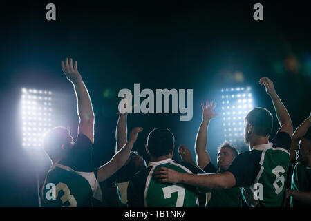 Gruppe von Rugby-Teamspielern, die den Sieg in der Sportarena unter Licht bejubelt. rugbyspieler feiern den Sieg. Stockfoto