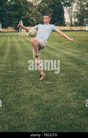 Junge Spieler üben Ballkontrolle mit einem Fußball das Aufprallen auf seinem Oberschenkel während der Ausbildung her einem Spiel oder Wettbewerb auf einem Sportplatz Stockfoto