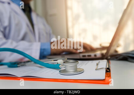 Close-up Stethoskop liegt in der Zwischenablage in der Nähe einen Arzt der Texteingabe auf Laptop Stockfoto
