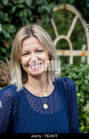 Frau mit blonden Haaren und trägt blaue oben stehend im Freien, ein Lächeln auf die Kamera. Stockfoto