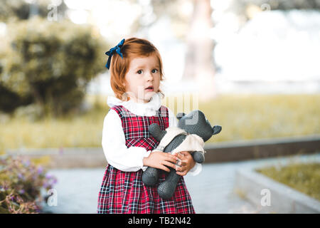 Cute Baby Mädchen 1-2 Jahre alten Holding Teddybär im Freien. Mit Blick auf die Kamera. Kindheit. Stockfoto