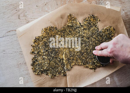 Hohen Winkel in der Nähe der Person trennscheiben der gesäten cracker Teig. Stockfoto