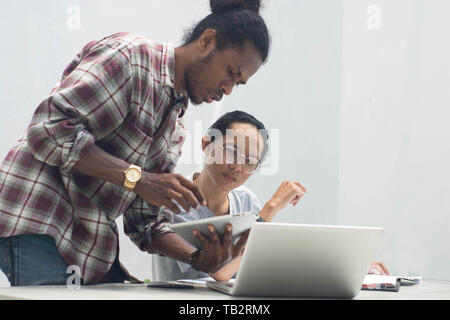 Zwei Freund mit unterschiedlichen ethnischen zusammen mit Notebook und Tablet-PC etwas diskutieren, zwei junge Menschen arbeiten und gemeinsam studieren Stockfoto