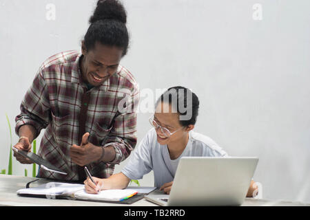 Zwei Freund mit unterschiedlichen ethnischen zusammen mit Notebook und Tablet-PC etwas diskutieren, zwei junge Menschen arbeiten und miteinander studiert und ich Stockfoto