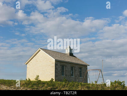 Tallgrass Prairie Preserve, einem historischen Schule Haus Gebäude und einer Pappel Baum und eine Reihe von rostigen Schaukel, im Frühling. Stockfoto