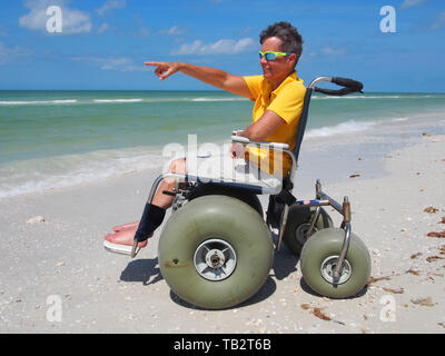 Behinderte Frau in Strandrollstuhl geniesst die Sonne und Sand auf Honeymoon Island State Park in Dunedin, Florida, USA, 10. Mai 2019, © katharine Andrioti Stockfoto