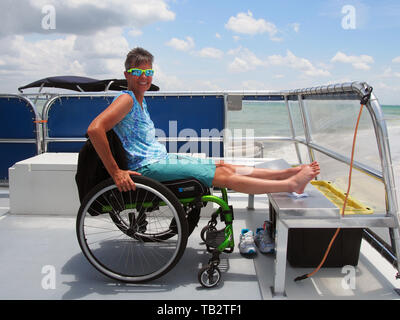 Behinderte Frau im Rollstuhl genießt eine Bootsfahrt, Florida, USA, 9. Mai 2019, © katharine Andriotis Stockfoto