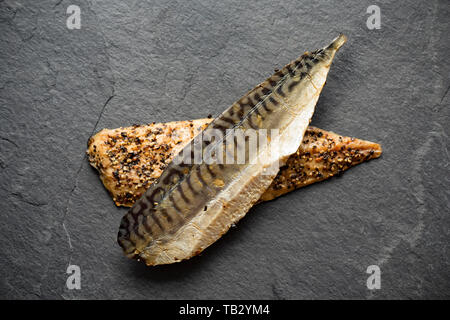 Zwei heiße, geräucherte Makrelenfilets aus Schottland, S. scombrus, mit geknacktem schwarzem Pfeffer, die von einem Supermarkt in Großbritannien gekauft wurden. Makrele sind eine Quelle von Ome Stockfoto