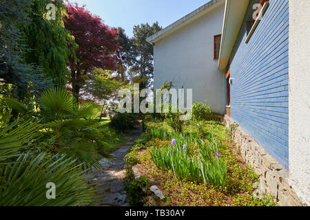 Garten und Villa mit Stein Fliesen- Pfad und Pflanzen in einem sonnigen Sommertag, Italien Stockfoto