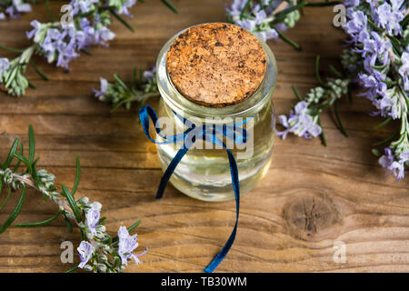 Rosmarin Öl in eine Flasche mit blume Filialen auf einem Tisch Stockfoto