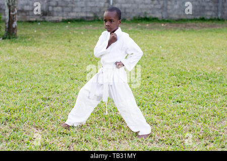 Kind in einem Kimono üben Karate alleine im Garten Stockfoto