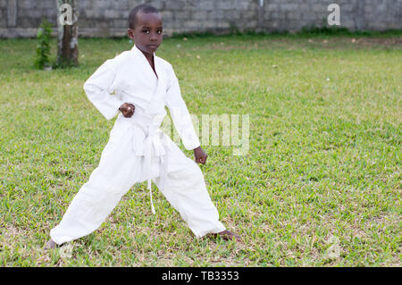 Profil eines kleinen Jungen in einem Kimono üben Karate alleine im Park Stockfoto