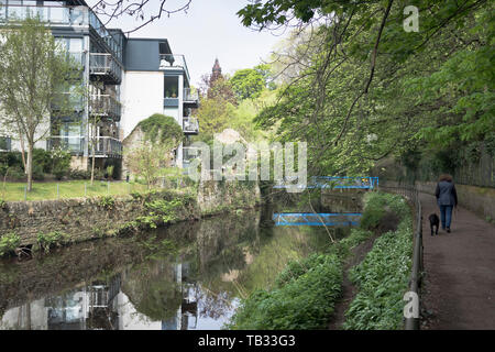 dh City Flussweg WASSER VON LEITH EDINBURGH Person zu Fuß Hund moderne Wohnung Wohnungen Gehweg Menschen Fußweg uk Spaziergang Flussufer Spaziergänge Stockfoto