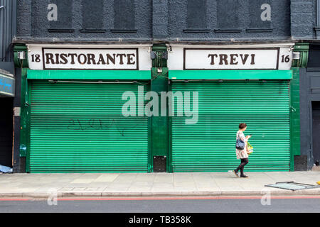 Eine Frau vorbei Ristorante Trevi, einem italienischen Restaurant in Highbury Corner, geschlossen mit seinen grünen-lackiertem Metall Rollläden runter, London, UK Stockfoto