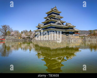 Schloß Matsumoto spiegelt sich in einen stillen See und dem klaren, blauen Himmel Hintergrund Stockfoto