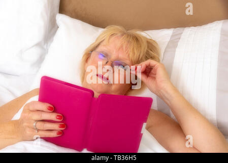 Portsmouth, England, Großbritannien 2019. Eine elederly Frau im Bett mit einem ipad Stockfoto