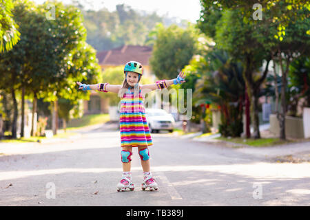 Kind auf Inline Skates in Park. Kinder lernen roller blades zu skaten. Kleines Mädchen skaten am sonnigen Sommertag. Aktivität im Freien für Kinder zum sicheren Resi Stockfoto