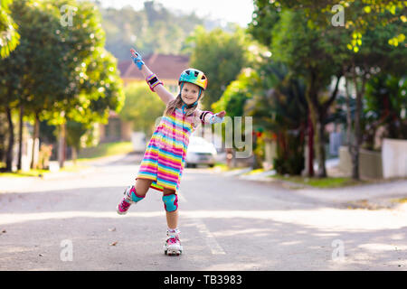 Kind auf Inline Skates in Park. Kinder lernen roller blades zu skaten. Kleines Mädchen skaten am sonnigen Sommertag. Aktivität im Freien für Kinder zum sicheren Resi Stockfoto