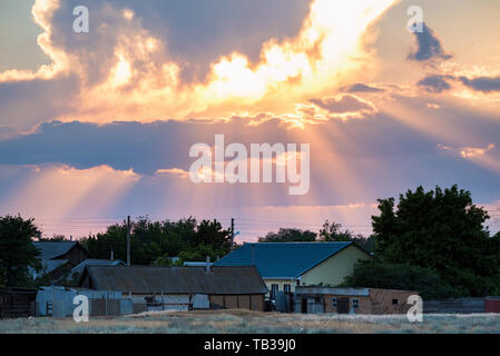 Dramatische Wolkenhimmel mit Sonnenstrahlen fallen auf coutry Haus Stockfoto