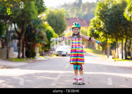 Kind auf Inline Skates in Park. Kinder lernen roller blades zu skaten. Kleines Mädchen skaten am sonnigen Sommertag. Aktivität im Freien für Kinder zum sicheren Resi Stockfoto