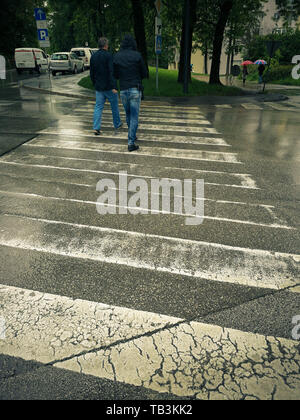Menschen auf dem Weg zu Fuß ein Dalmatiner Hund im Regen auf der Straße geparkten Autos. Stockfoto