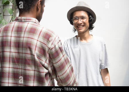 Jungen asiatischen Mann die Hand schütteln mit Freund als Vordergrund, jungen asiatischen Mann mit Brille Handshake mit schwarzer Mann Stockfoto