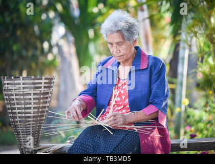 Asien leben alte Frau in Home/Großmutter schwere Leben auf dem Land das Leben der ländlichen Bevölkerung in Thailand Webart Bambus Warenkorb Handwerk arbeiten Stockfoto