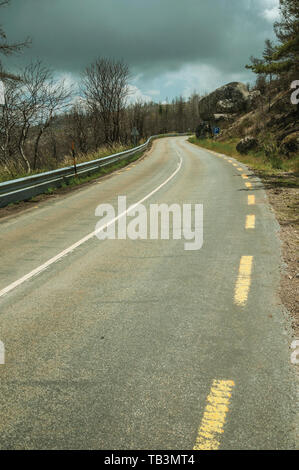 Gepflasterte Straße, die durch einen verbrannten Waldes über einen felsigen Landschaft der Serra da Estrela. Das höchste Gebirge auf dem portugiesischen Festland. Stockfoto
