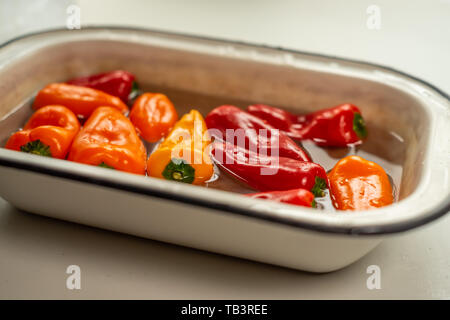 Bunte Paprika in Wasser in vintage Emaille Schüssel. Nahaufnahme Stockfoto