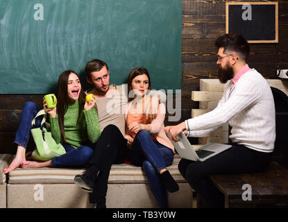 Hochschule und Universität Konzept. Studenten, Wissenschaftler, die studieren, Professor Laptop hält, unterrichtet, erklärt, schwarzes Brett Hintergrund. Gruppe von Studenten, g Stockfoto