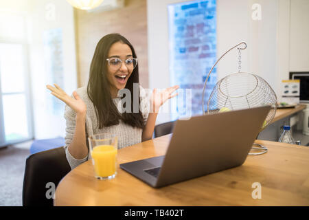 Bild von schockiert nette junge hübsche Frau steht in der Küche zuhause zu Hause mit Laptop Computer kochen. Stockfoto
