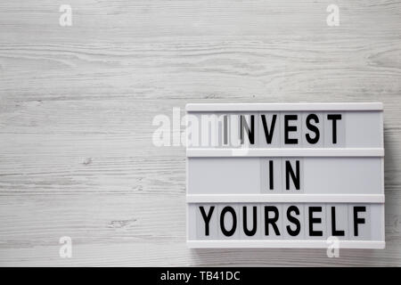 Lightbox mit 'Investieren in sich selbst die Worte über weiß Holz- Hintergrund, Ansicht von oben. Overhead, flach, von oben. Kopieren Sie Platz. Stockfoto